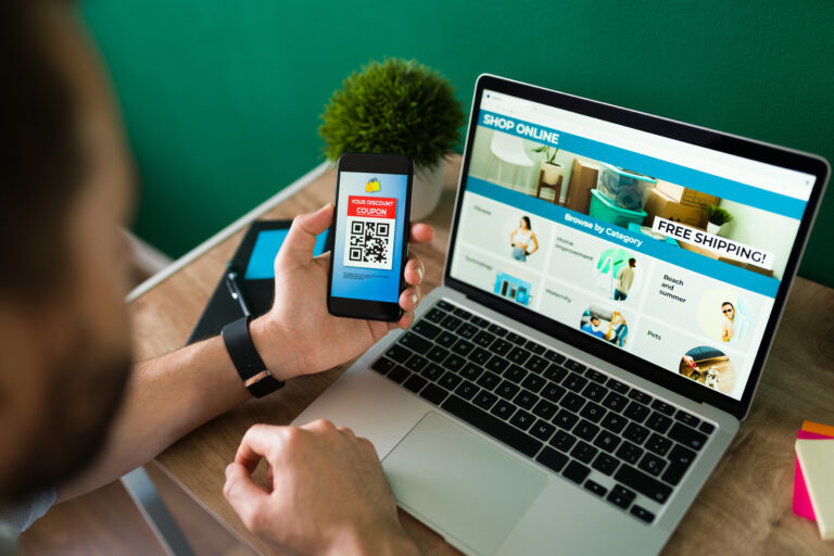 young man using discount coupon his smartphone some online shopping laptop